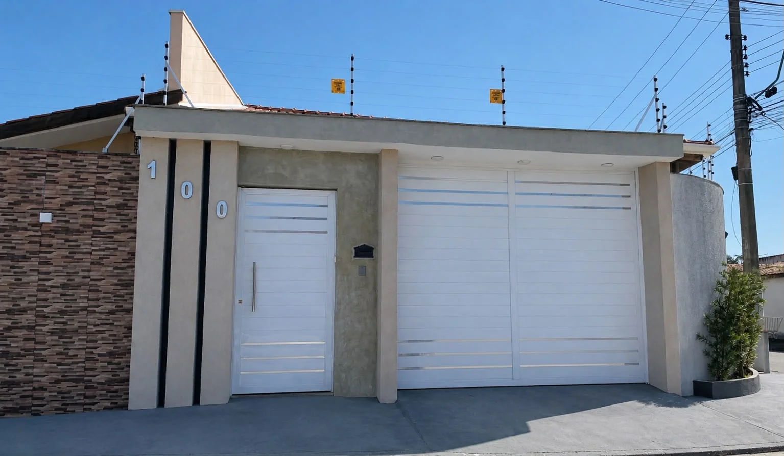 Fachada de uma residência finalizada com revestimento, portão e garagem brancos