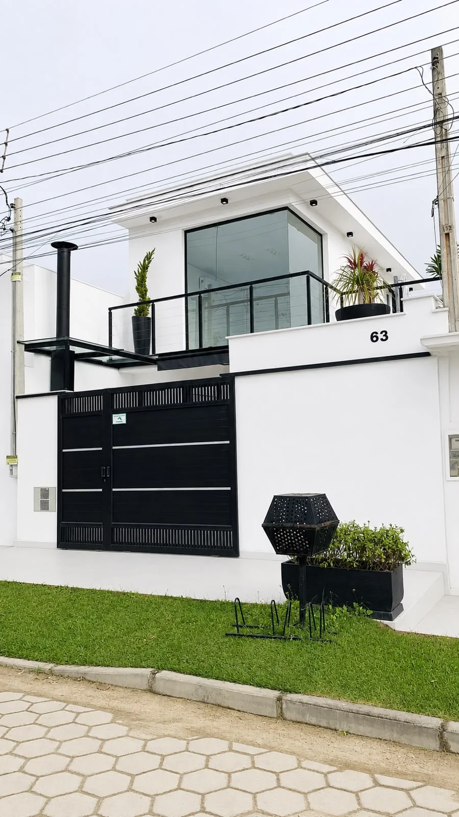 Fachada de uma residência contemporânea concluída, com acabamento branco e esquadrias escuras